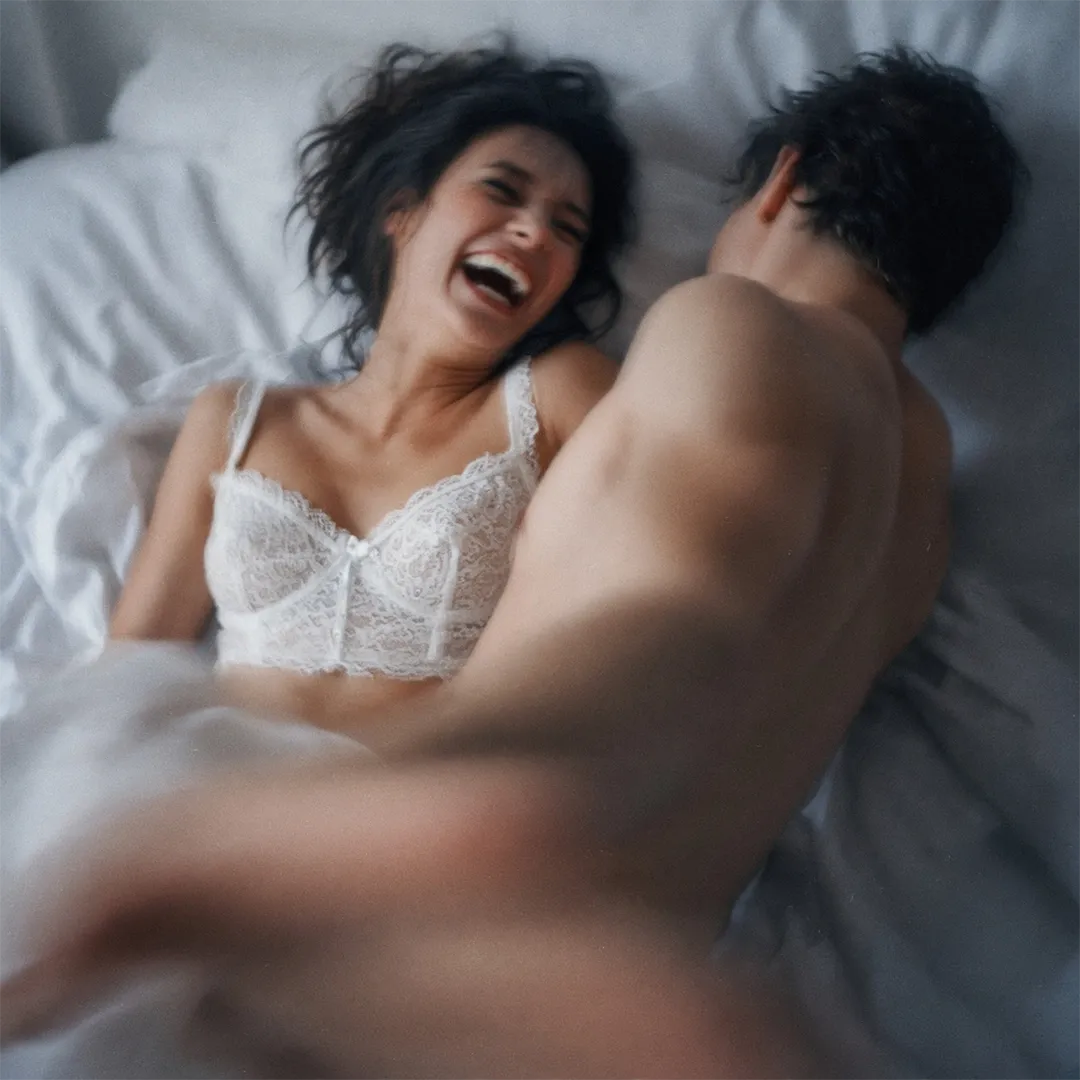 A couple laughing together in bed
